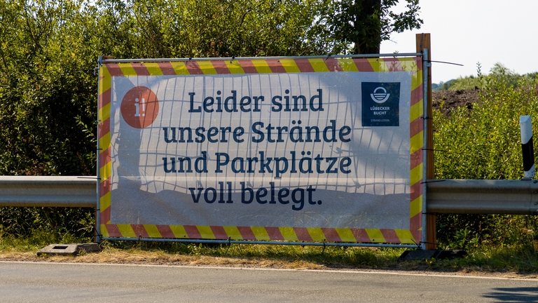 Banner "Leider sind unsere Strände und Parkplätze voll belegt" an der Lübecker Bucht