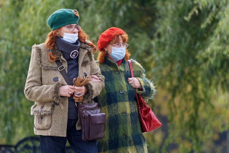 zwei Frauen warten vor der Impfstelle mit Maske